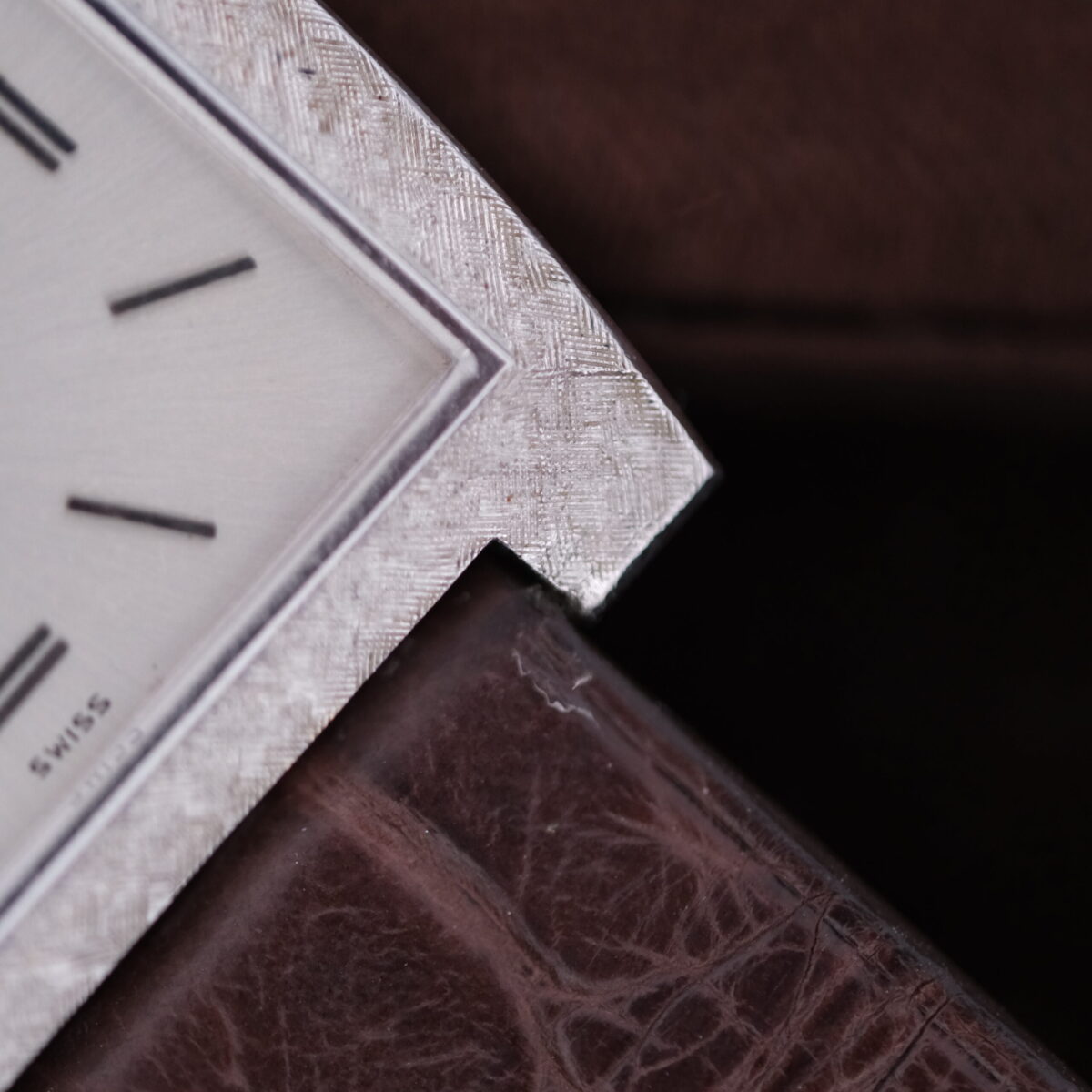 A close-up of the Vacheron Constantin 6761 Cal 1003 reveals its vintage watch face with Roman numerals set in a textured silver frame, exuding timeless elegance against a dark, textured leather surface.